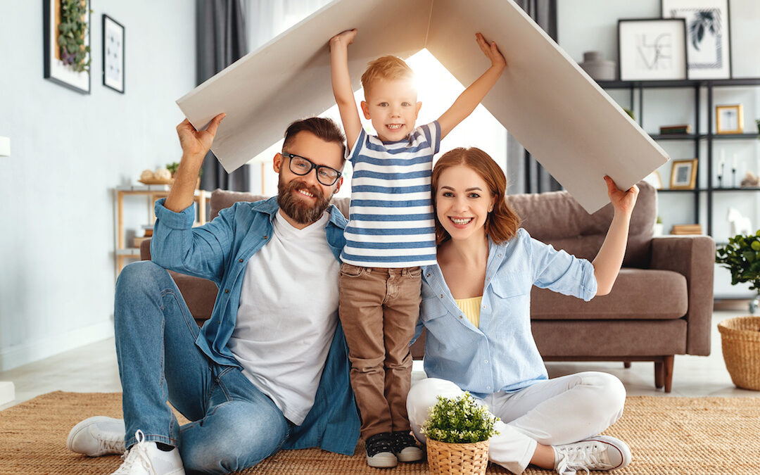 Couple with child sit under a child's playhouse roof to symbolize estate planning