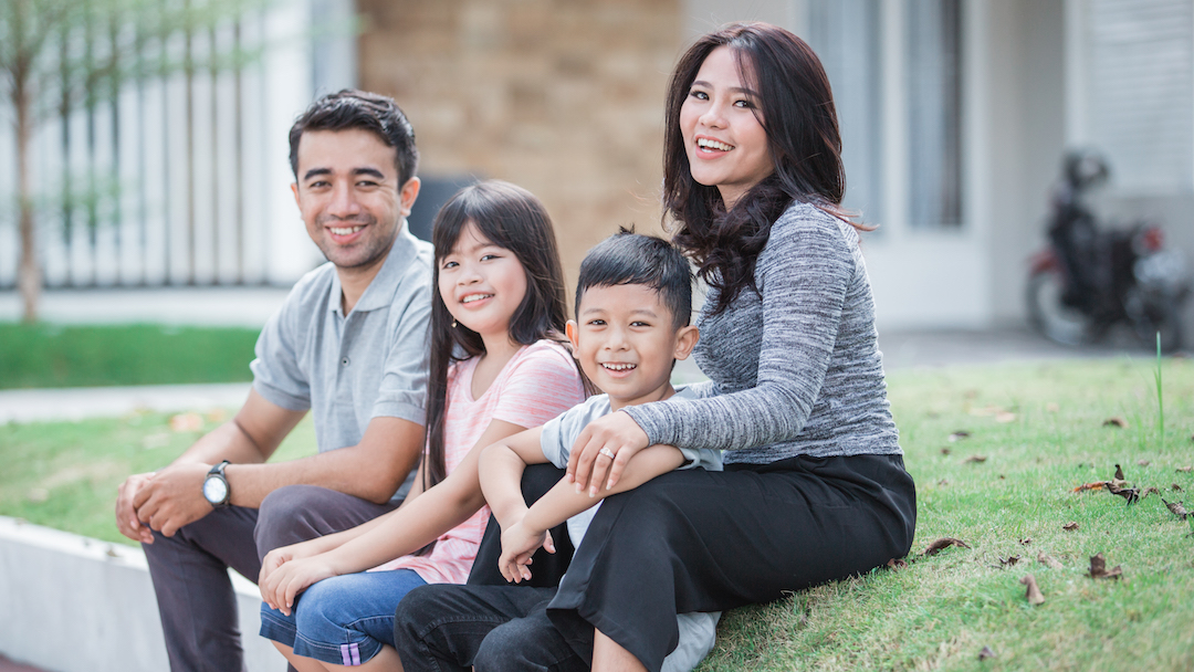 Happy young Asian family in front of home
